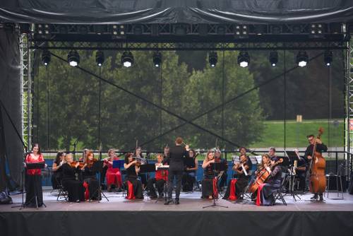 Muzycy podczas koncertu na scenie. Stroje czarno-czerwone. Szeroki kadr.