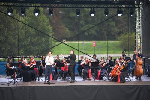 Muzycy podczas koncertu na scenie. Stroje czarno-czerwone. Szeroki kadr.