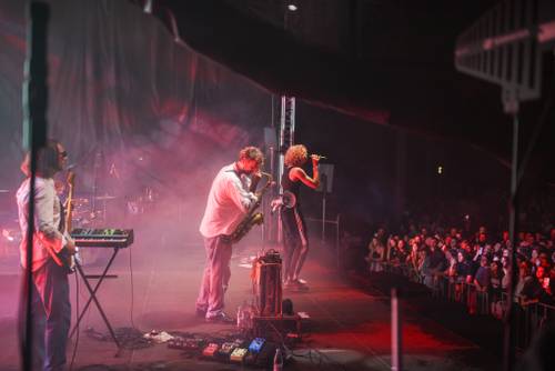 Koncert Szczyla. Raper i muzycy na scenie. Publiczność pod sceną bawi się podczas koncertu.