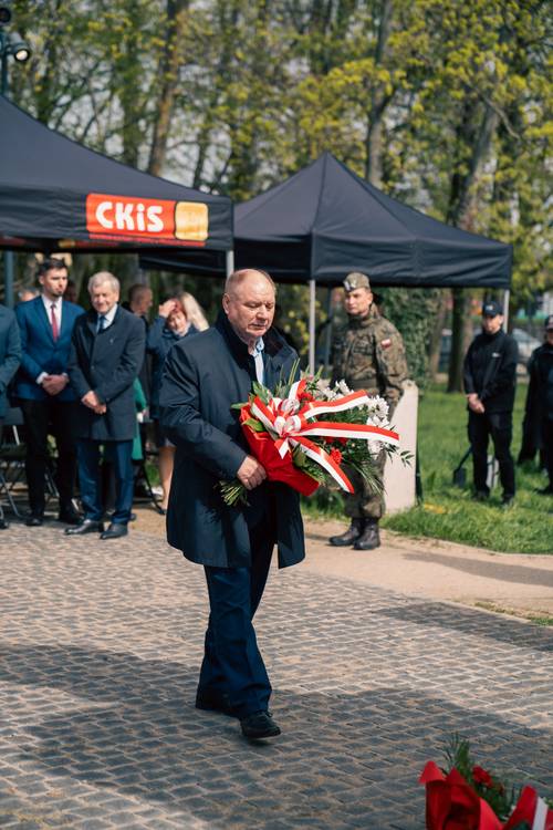 Stefan Skonieczny składa kwiaty podczas obchodów upamiętniających zbrodnię katyńską w obstawie żołnierzy.