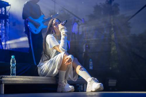 Sara James siedzi na scenie. W tle gitarzysta,