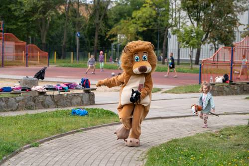 Lew Pruszek i dziecko bawiące się hobby horse podczas festynu Wakacje w mieście na boisku przy ulicy Tysiąclecia.