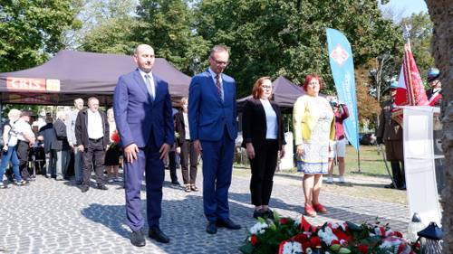 Składanie kwiatów pod pomnikiem przez gości.