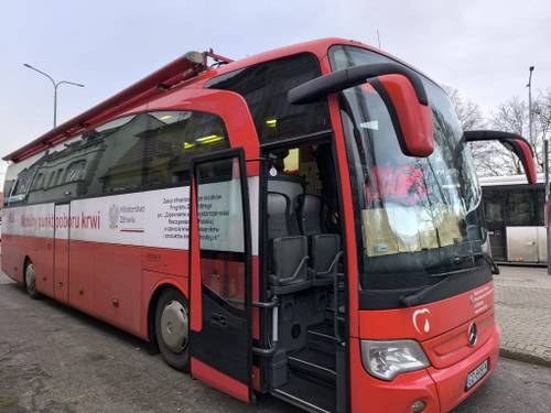 Autobus, cały czerwony, z białym pasem w poprzek, to krwiobus, w którym pobierana jest krew.