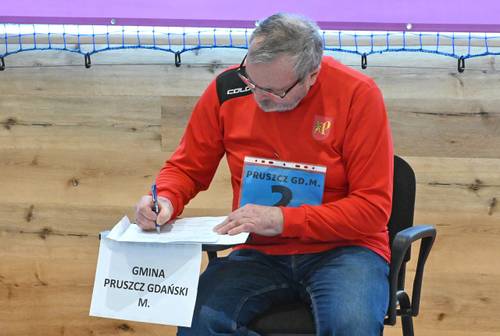 Mężczyzna w czerwonej koszulce siedzi przy stoliku i rozwiązuje test.