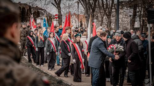 Goście składają kwiaty podczas uroczystości.