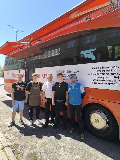 Organizatorzy i partnerzy stoją przed autobusem.