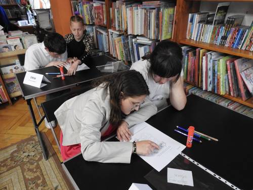 Dzieci wykonujące zadania konkursowe w bibliotece