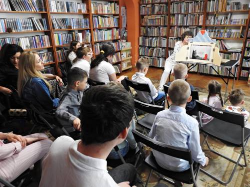 Dzieci oglądają w bibliotece teatrzyk Czerwony Kapturek