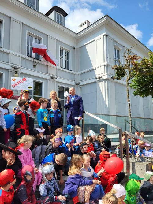 Dzieci w strojach superbohaterów siedzą na schodach Urzędu Miasta. Zbliżenie.