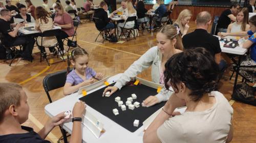 Rozgrywki Rummikub, zawodnicy siedzą przy stolikach