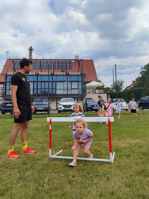 Zabawy ruchowe dzieci na świeżym powietrzu, dziewczynka biegnie pod bramką