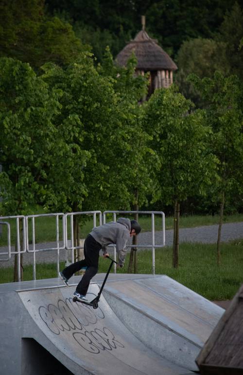 Skatepark - nastolatek robi ewolucje na hulajnodze.