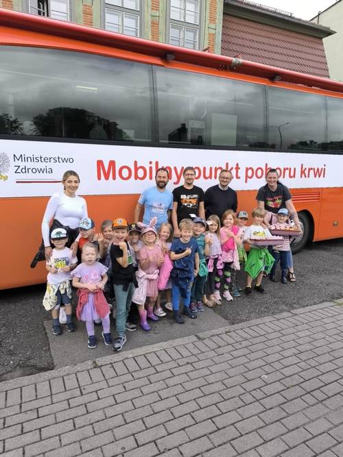 Organizatorzy, przedszkolaki i nauczycielki przed busem.