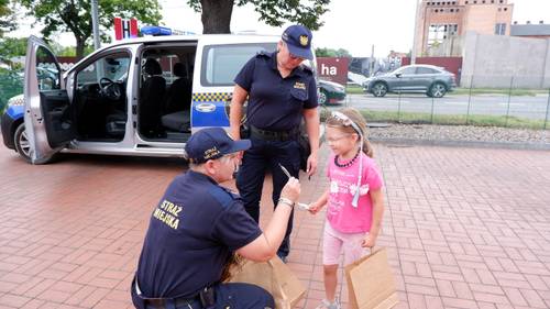 Strażniczki miejskie wręczają dziewczynce upominek
