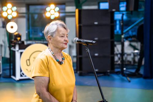 Przemówienie kobiety w żółtej bluzce.