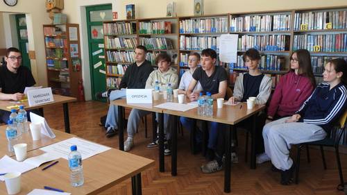 Grupa uczniów siedzi przy stole i prowadzi dyskusję