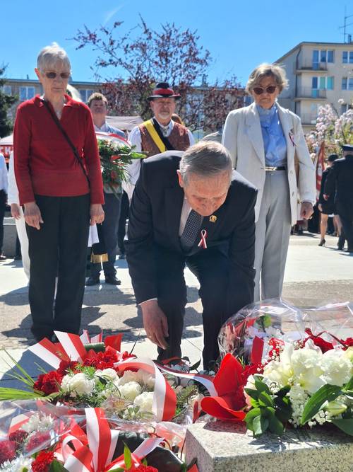 Uczestnicy uroczystości składają kwiaty pod pomnikiem Nike