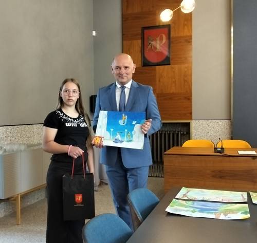 Jedna z laureatek z zastępcą burmistrza trzymającym pracę