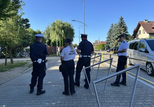 Policjanci i strażnicy miejscy stoją przed szkołą