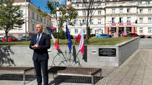 Starosta gdański stoi przed flagami i tablicą pamiątkową