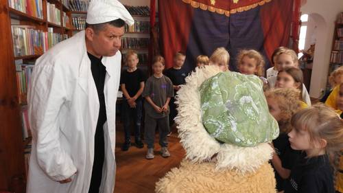 Zbliżenie na mężczyznę w białym fartuchu u czapce, obok grupka dzieci