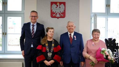 Dwóch panów i dwie panie stoją pod godłem