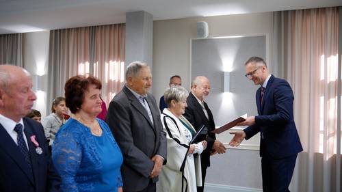 Burmistrz Pruszcza Gdańskiego wręcza jednej z par dyplom, obok stoją pozostali jubilaci