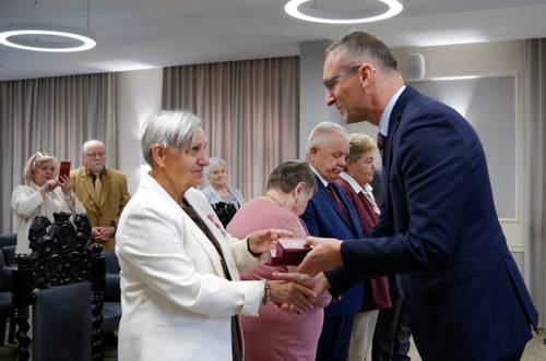 Burmistrz Pruszcza wręcza starszej pani pudełko