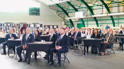 Widok na salę i ludzi siedzących przy czarnych stolikach