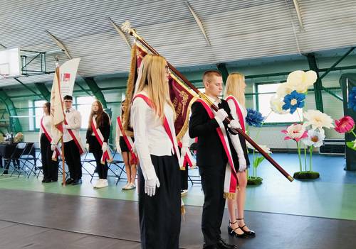 Zbliżenie na poczet sztandarowy, chłopiec stojący w środku trzyma na ramieniu sztandar