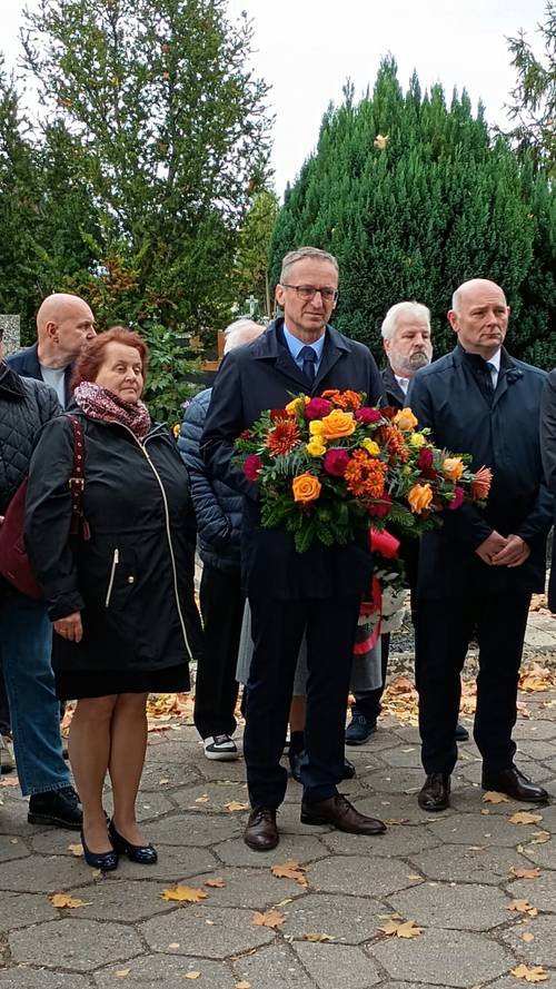 Zbliżenie na kobietę i kilku mężczyzn, z których jeden trzyma wiązankę kwiatów