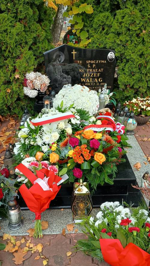 Pomnik księdza Józefa Waląga z wiązankami kwiatów i zniczami