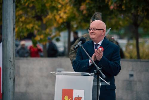 Mężczyzna za mównicą, który klaszcze.