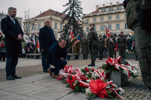 Uczestnicy składający kwiaty pod pomnikiem.