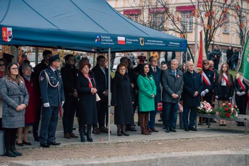 Uczestnicy stojący pod zadaszeniem w trakcie uroczystości.